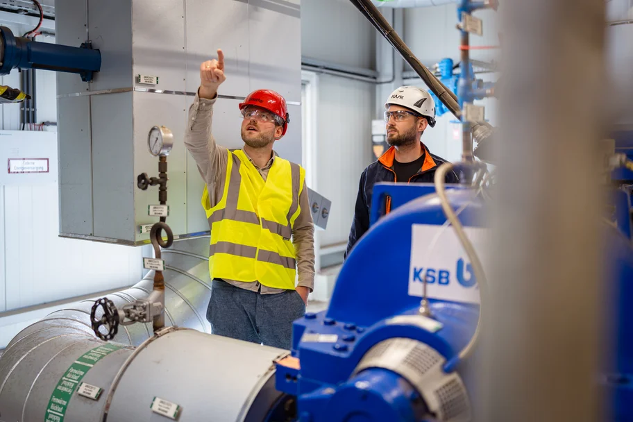 The project managers at one of the district heating heat pumps at the EEW Hannover district heating transfer station.